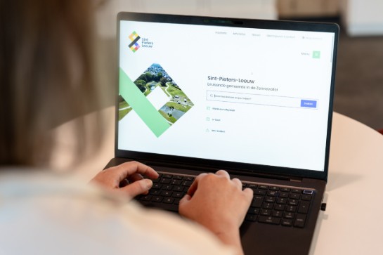Persoon werkt op laptop met website van Sint-Pieters-Leeuw, gemeente in de Zennevallei, geopend. (vergroot foto)