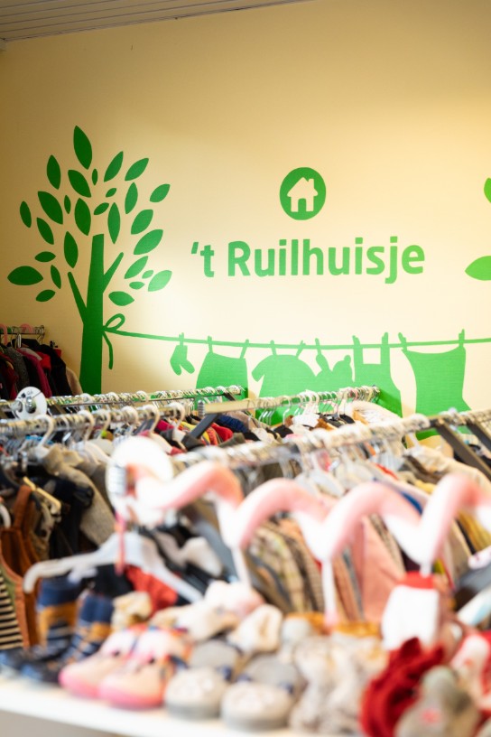 Interieur van 't Ruilhuisje met rekken vol tweedehands kinderkleding en schoenen. (vergroot foto)