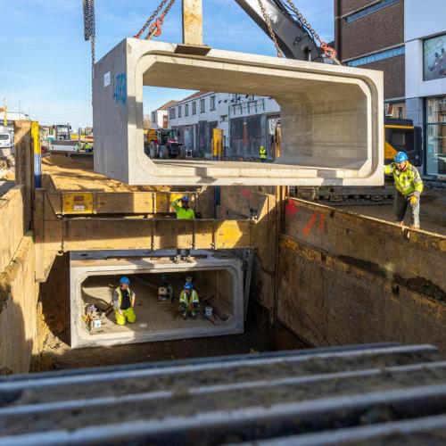 Met een mobiele telescoopkraan van 80 ton worden iedere werkdag drie rioleringskokers geplaatst.   ©Agentschap Wegen en Verkeer